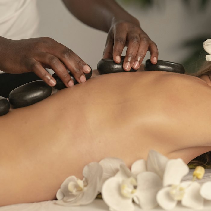 A hot stone massage in progress, orchids laid along the table.