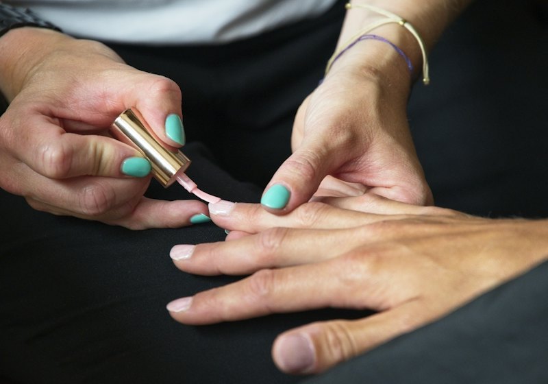 A manicurist painting a client's nails.